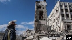 Rescatistas trabajan entre los escombros de un edificio oficial dañado por las bombas, en Járkiv, Ucrania, el 18 de marzo de 2022. (AP Foto/Andrew Marienko)