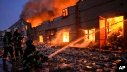 Ukrainian firefighters extinguish a blaze at a warehouse after a bombing in Kyiv, March 17, 2022.