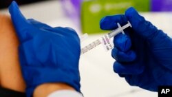 FILE - A health worker administers a dose of a Moderna COVID-19 vaccine during a vaccination clinic at the Norristown Public Health Center in Norristown, Pennsylvania, Dec. 7, 2021.