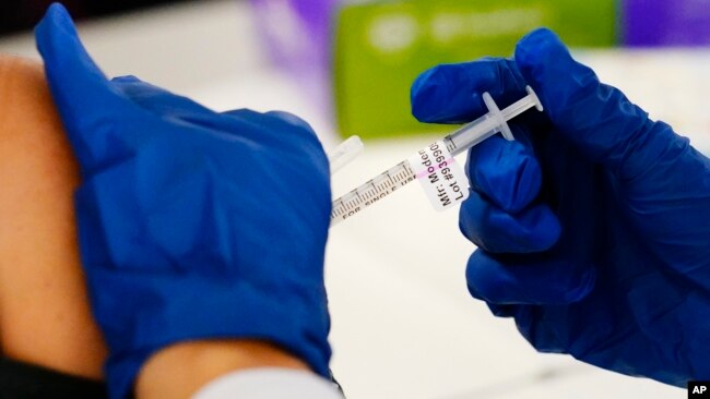 FILE - A health worker administers a dose of a Moderna COVID-19 vaccine during a vaccination clinic at the Norristown Public Health Center in Norristown, Pennsylvania, Dec. 7, 2021.