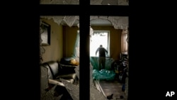 Slava Chikov covers the shattered window of his living room with a plastic sheet in a building damaged by a bombing the previous day in Kyiv, Ukraine, March 21, 2022. 