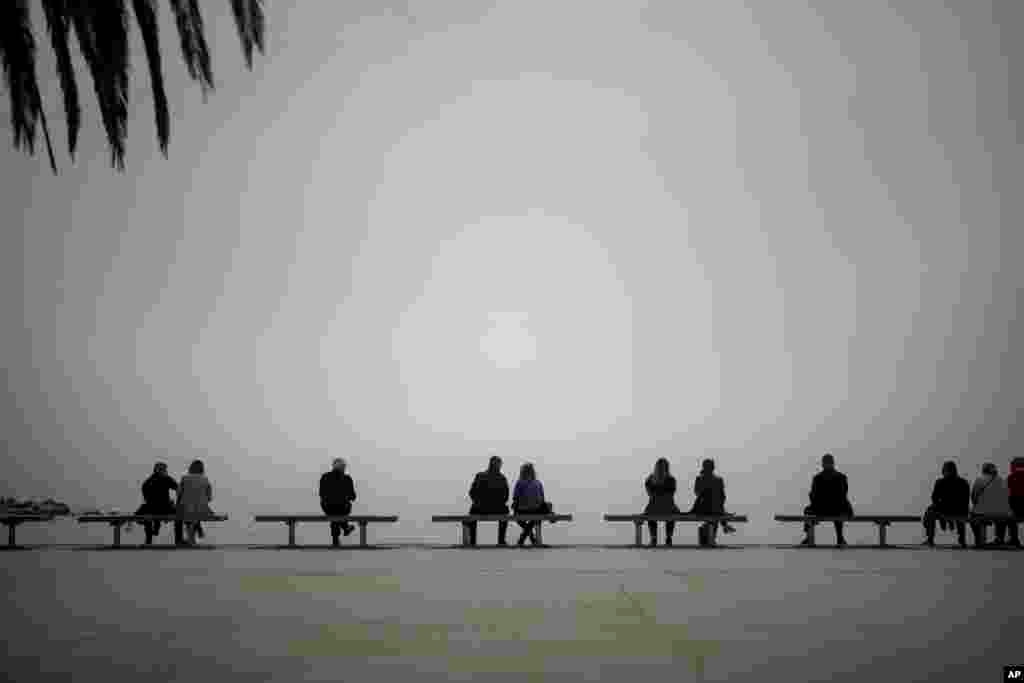 People sit and enjoy watching the Mediterranean sea in Barcelona, Spain.