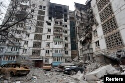 Destroyed cars are seen in front of an apartment building which was heavily damaged during Ukraine-Russia conflict in the besieged southern port city of Mariupol, March 27, 2022.