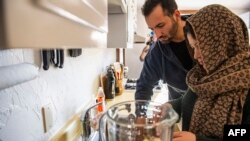 Afghani evacuees Israr, 26, and his wife Sayeda, 23, make a morning smoothie of fruit, nuts and milk, an American concept her and her husband Israr have been trying for a few weeks instead of tea, at their new apartment in Charlestown, Massachusetts on February 21, 2022.