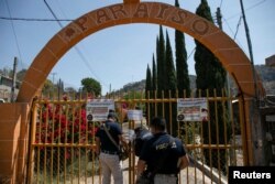 Un agente de la Procuraduría General de Justicia de Michoacán coloca un candado y una cadena en la puerta de una red clandestina de peleas de gallos luego de la muerte de al menos 20 personas el domingo por la noche durante un ataque, dijeron las autoridades, en Zinapécuaro, México, el 28 de marzo de 2022.