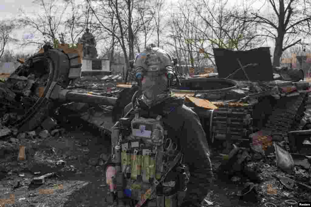 A Ukranian serviceman walks past the wreckage of a Russian tank in the village of Lukyanivka outside Kyiv, as Russia&#39;s invasion of Ukraine continues, March 27, 2022.