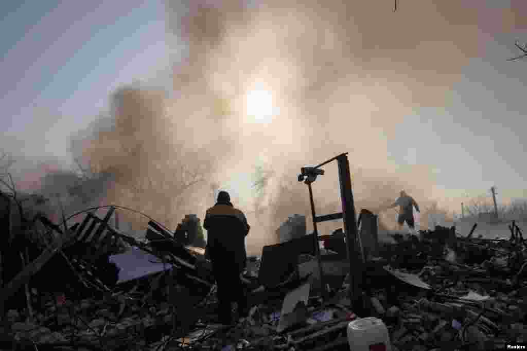Los residentes apagan un incendio después de que un bombardeo destruyera una casa familiar en un distrito del norte de Járkov.