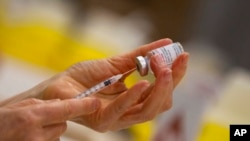 FILE - A pharmacist fills a syringe from a vial of the Moderna COVID-19 vaccine in Antwerp, Belgium, April 14, 2021. Moderna and vaccine promoter Gavi announced last may that the company would provide up to 500 million coronavirus vaccine doses for the U.