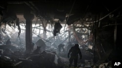 پس از بمب گذاری در کیف، کارمندان اطفاییه و نیروهای خدمات اوکراینی در جستجوی افراد زیر آوار در داخل یک فروشگاه هستند