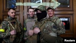FILE - Four foreign fighters from the UK pose for a picture prior to their departure towards the front line in the east of Ukraine following the Russia's invasion, at the main train station in Lviv, western Ukraine, March 5, 2022. 