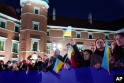 People listen as U.S. President Joe Biden delivers a speech about the Russian invasion of Ukraine, at the Royal Castle, March 26, 2022, in Warsaw.