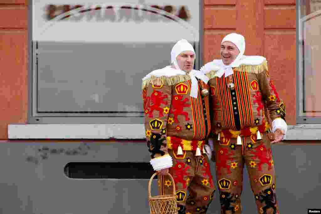 People wearing costumes stand near the site where a vehicle drove into a group of Belgian carnival performers who were preparing for a parade in the village of Strepy-Bracquegnies, Belgium.