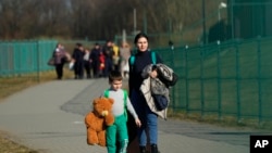 На фото: Середа, 23 березня 2022 року, українські біженці проходять через прикордонний перехід на південному сході Польщі