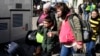 Refugiados ucranianos con niños abordan el transporte en una plaza junto a una estación de tren en Przemysl, Polonia, el martes 22 de marzo de 2022. [Foto AP/Sergei Grits]