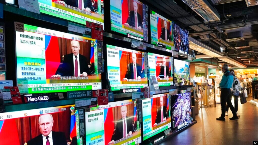 FILE - People stand by TV screens broadcasting the news of Russian troops that have launched their attack on Ukraine, in Hong Kong, Feb. 24, 2022. 资料照： 2022年2月24日，香港，人们站在播放着俄罗斯军队对乌克兰发动攻击的新闻的电视屏幕前。（美联社）(photo:VOA)