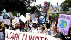 Anak-anak sekolah meneriakkan slogan-slogan di depan rumah Perdana Menteri Australia Scott Morrison di Sydney, 25 Maret 2022, dalam aksi mogok dan protes oleh siswa, menyoroti kemajuan yang tidak memadai untuk mengatasi perubahan iklim. (Muhammad FAROOQ/AFP)