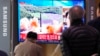 Ljudi gledaju TV program i emisiju veti tokom koje je prikazana arhivsta fotografija severnokorejskog lansiranja rakete, na železničkoj stanici u Seulu, Južna Koreja, 24. marta 2022.