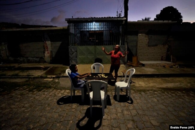 Quiteria Maria da Silva, with her grandson, Luri Andriel, calls up to her family. Da Silva is the last resident on her street, March 6, 2022. (AP Photo/Eraldo Peres)