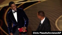 Komedian Chris Rock (kiri) bereaksi setelah aktor Will Smith menamparnya di atas panggung dalam ajang Oscar yang digelar di Los Angeles, California, pada 27 Maret 2022. (Foto: AP/Chriss Pizzello)