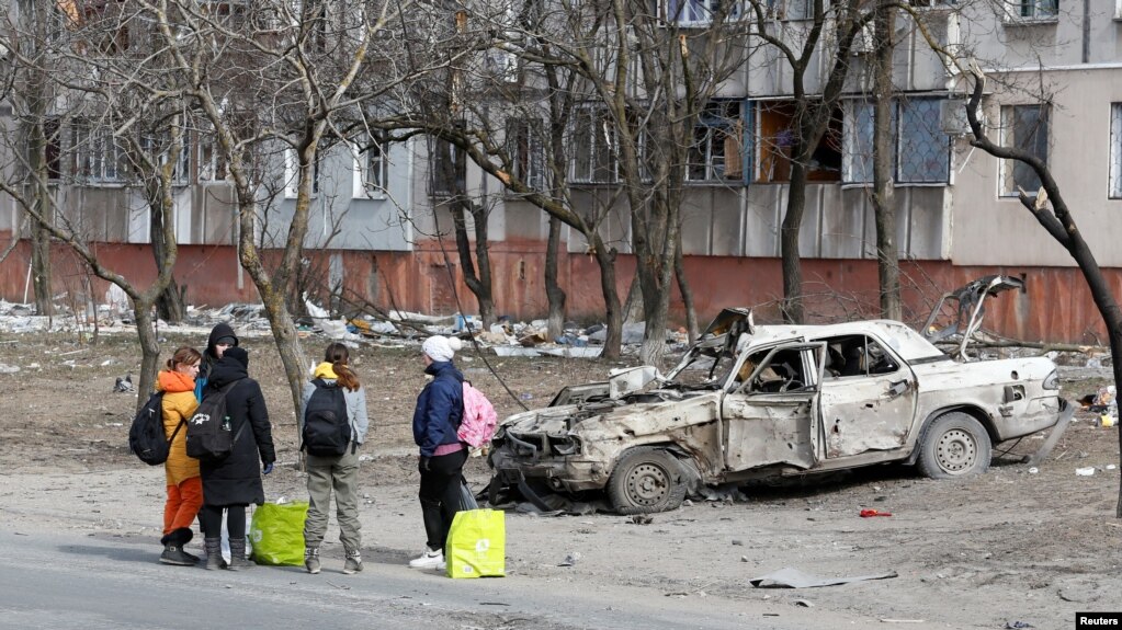 Refugees gather in a street as they leave the besieged southern port of Mariupol, Ukraine, March 20, 2022. (REUTERS/Alexander Ermochenko)