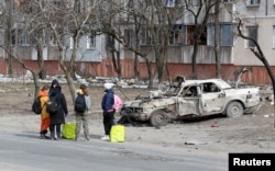 Refugees gather in a street as they leave the besieged southern port of Mariupol, Ukraine, March 20, 2022.