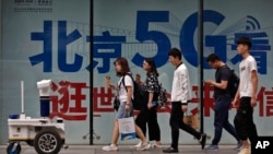 人们在北京街头一个购物区的5G网络广告前走过。（2019年5月15日）