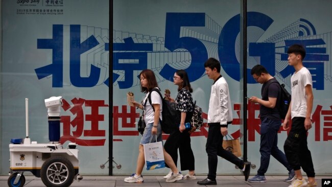 人们在北京街头一个购物区的5G网络广告前走过。（2019年5月15日）