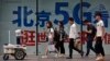 People walk toward a police robot mounted with surveillance cameras patrol past a 5G network advertisement at a shopping district in Beijing, Wednesday, May 15, 2019. U.S. officials listed $300 billion more of Chinese goods for possible tariff hikes…