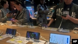 Orang-orang mencoba model ponsel pintar Huawei yang dipamerkan di toko elektronik di Beijing, 20 Mei 2019 (foto: AP Photo/Andy Wong)