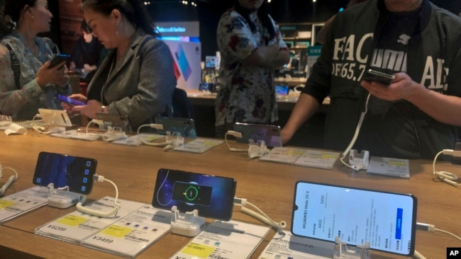 2019年5月20人们在北京的一家电子商店试用华为智能手机。