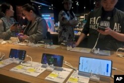 People try out Huawei smartphone models on display at an electronic store in Beijing, May 20, 2019.