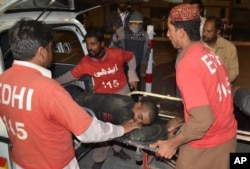 FILE - Pakistani volunteers rush an injured person to a hospital in Quetta, Pakistan, Oct. 24, 2016, after two separate attacks in Pakistan. Gunmen stormed a police training center in the southwestern province of Baluchistan Monday, leaving several people woun