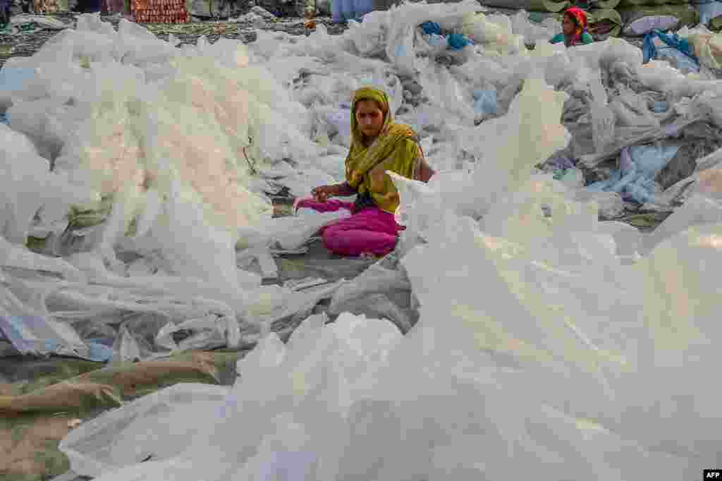 A laborer arranges plastic bags used to carry industrial chemicals to dry out by the Buriganga River in Dhaka, Bangladesh.