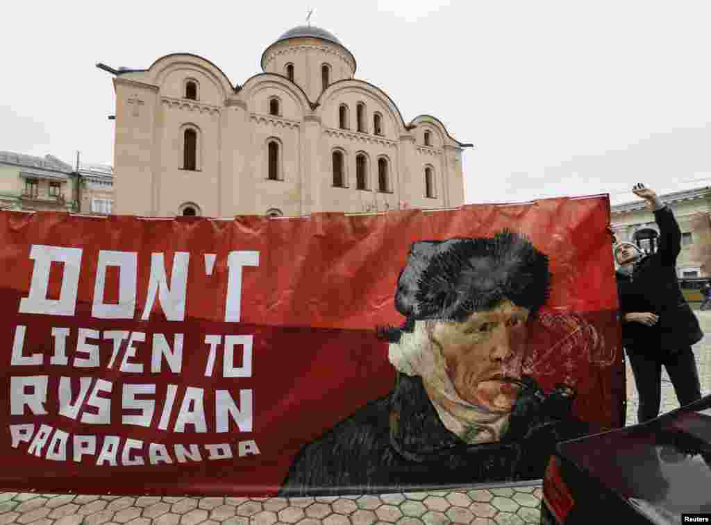 An activist holds a banner with a portrait of Dutch artist Vincent van Gogh as he demonstrates outside the Dutch embassy in Kyiv, Ukraine. The activists demand that Dutch people ignore what they say is propaganda, ahead of an upcoming Dutch Ukraine-EU Association Agreement.
