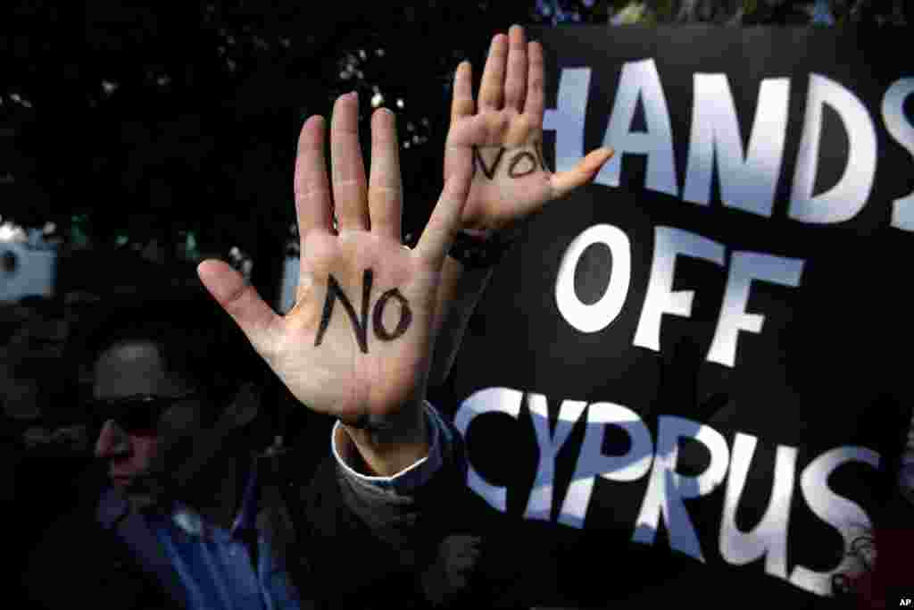 Protesters hold up their hands as they protest outside the parliament in capital Nicosia, Cyprus, March 18, 2013.