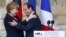 German Chancellor Angela Merkel, and French President Francois Hollande react after a speech in front of the Reims cathedral in Reims, eastern France, July 8, 2012. 