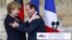 German Chancellor Angela Merkel, and French President Francois Hollande react after a speech in front of the Reims cathedral in Reims, eastern France, July 8, 2012. 