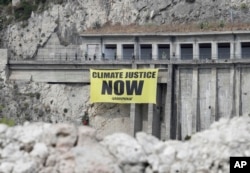 Greenpeace activists hang a banner on climate issues along a road above the beach of Isolabella, ahead of a G-7 summit scheduled for May 26 and 27, in the Sicilian town of Taormina, May 25, 2017.