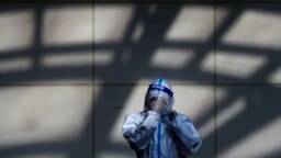 Un trabajador con traje protector se limpia el protector facial en un lado de pruebas de coronavirus en Beijing, el lunes 5 de diciembre de 2022.