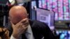 Un trader a la tête dans sa main sur le sol de la Bourse de New York, le jeudi 12 mars 2020. (AP Photo/Richard Drew)