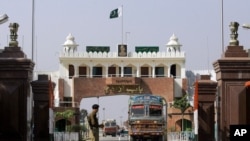 FILE - An Indian border security force soldier stands guard as an Indian truck, exporting goods to Pakistan, returns back towards the Indian side of joint check post between India and Pakistan at Wagah, India.