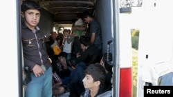FILE - Migrants sit inside a van after being pulled over by police on the highway near Gyor, Hungary, Sept. 6, 2015. 