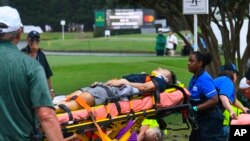 A spectator is taken to an ambulance after a lightning strike at East Lake Golf Club during a weather delay in the third round of the Tour Championship golf tournament, Aug. 24, 2019, in Atlanta. 