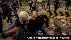 An injured police officer leaves the area with the help of his colleagues after clashes with protesters in Jakarta, Indonesia, early May 23, 2019. 