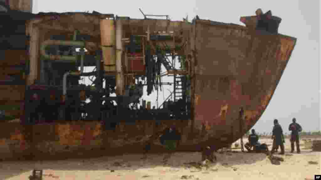 Workers gather in the shade of a derelict ship beached against the coastline of Nigeria.