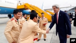 U.S. Secretary of State John Kerry greets police officers as he boards his plane at Hanoi airport, Jan. 13, 2017.