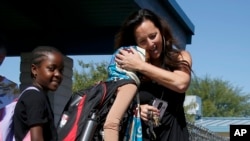 Director Lynette Faulkner, right, says goodbye to Durse Karayu, middle, and Riziki Nyongoco, left, students at Valencia Newcomer School at the end of the school day Thursday, Oct. 17, 2019, in Phoenix. (AP Photo/Ross D. Franklin)