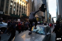A protester jumps on a car in midtown during demonstrations over the death of George Floyd by a Minneapolis police officer on June 1, 2020 in New York.