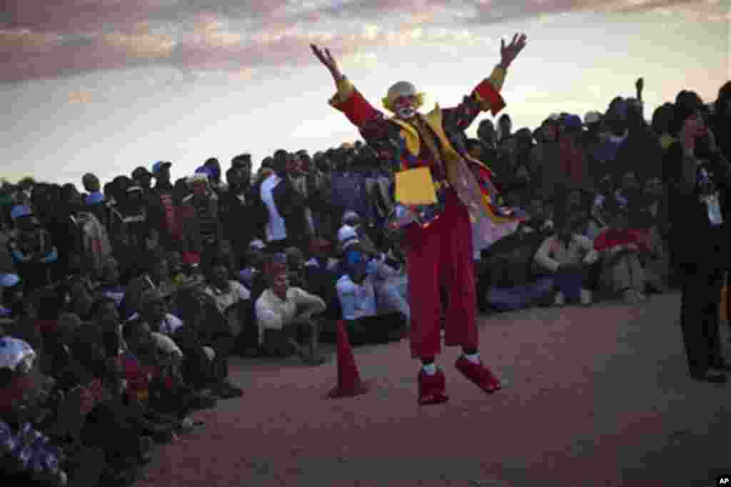 A clown performs to entertain people near to a refugee camp set up for displaced people who recently crossed over the border from into Tunisia, fleeing from the unrest in the Libya, in Ras Ajdir, Tunisia, March 20, 2011