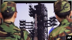 South Korean Army soldiers watch a TV news program which shows North Korea's Unha-3 rocket at Seoul train station in Seoul, South Korea, April 9, 2012